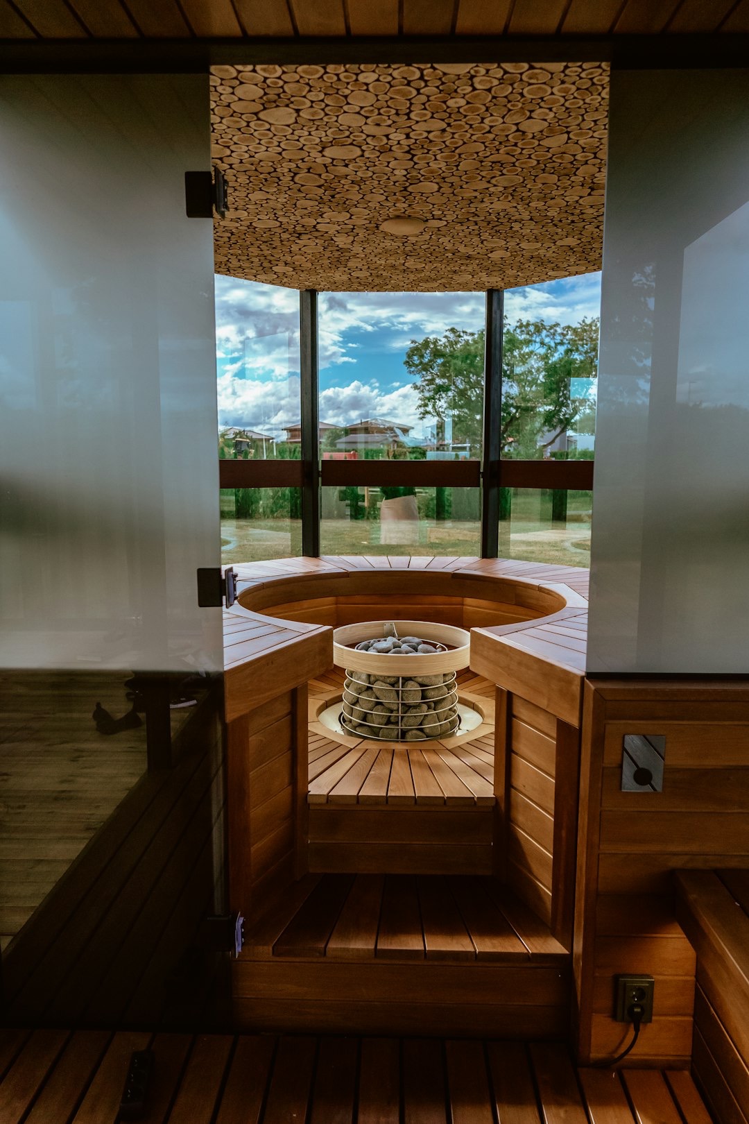 Modern sauna with a stone heater overlooking a green landscape.